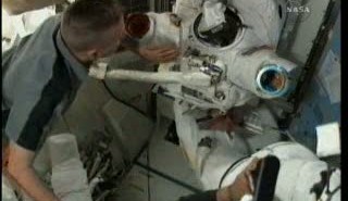 Astronauta Reisman (pod skafandrem kosmicznym - inni astronauci mu pomagają się rozebrać) / Credits - NASA TV