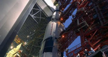 Czerwona wieża LUT zamontowana na transporterze przytrzymuje rakietę Saturn V, która właśnie opuszcza budynek VAB (NASA/69PC-0529)