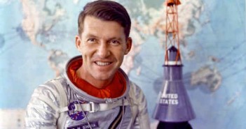 Astronauta Wally Schirra pozuje do zdjęcia w swoim skafandrze Navy Mk IV; w tle widoczna kapsuła Mercury (NASA/S62-05526)