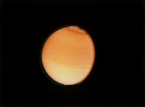 Zdjęcie wykonane przez sondę Voyager 2 (23 sierpnia 1981) przedstawia różnice jasności półkul Tytana. Wyraźnie ciemniejsza półkula północna świadczy o większym zgromadzeniu nad nią tholinowych oparów. (Credits: NASA/JPL)