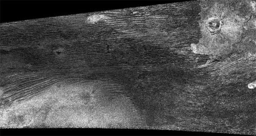 Radarowe zdjęcie powierzchni Tytana pozyskane 21 czerwca 2011 roku przez sondę Cassini. Jasny obszar w lewym dolnym rogu to twór powierzchniowy wielkości kontynentu - Xanadu. Faliste pasy powyżej to wydmy, podobne do tych z ziemskich pustyń. W prawym górnym rogu znajduje się krater Ksa. Credits: NASA/JPL