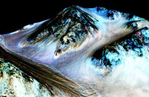 Ciemne, 100-metrowe smugi wskazują na występowanie płynnej wody na Marsie. Naukowcy odkryli uwodnione sole w ciemnych smugach. Niebieskie obszary to minerał piroksen, nie związany bezpośrednio z potokami solanki. Credits: NASA/JPL/University of Arizona