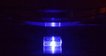 Pobudzany światłem niebieskim kryształ fluorku litu z zarejestrowanymi śladami cząstek jonizujących podczas obserwacji pod mikroskopem fluorescencyjnym. (Źródło: IFJ PAN)